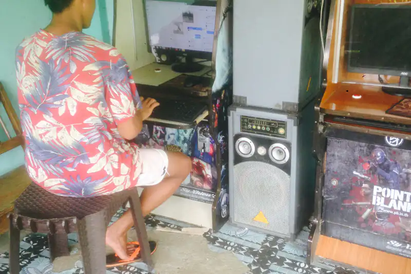 Young Filipino sitting at a coin-operated piso net computer